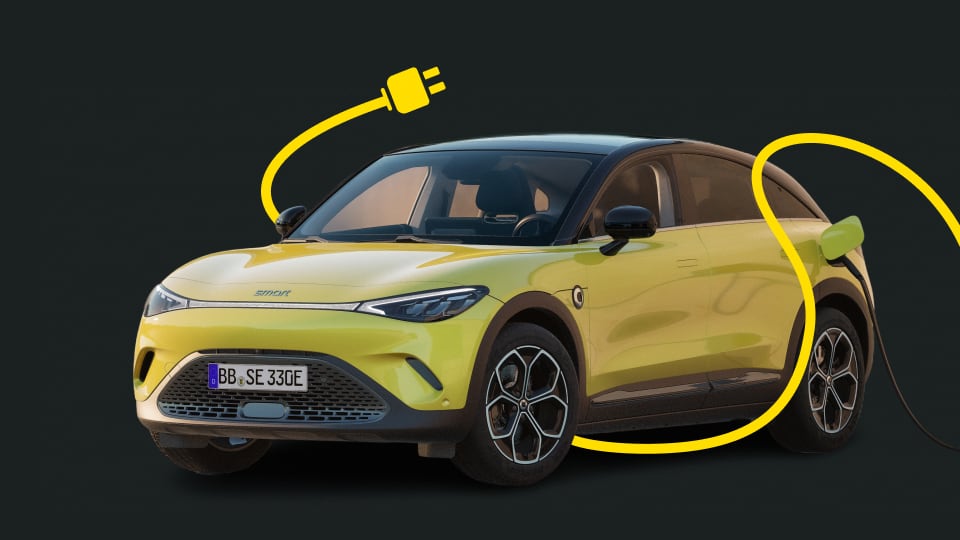 Yellow electric smart #3 car with black roof, plugged in and connected to a yellow power cord on a dark background